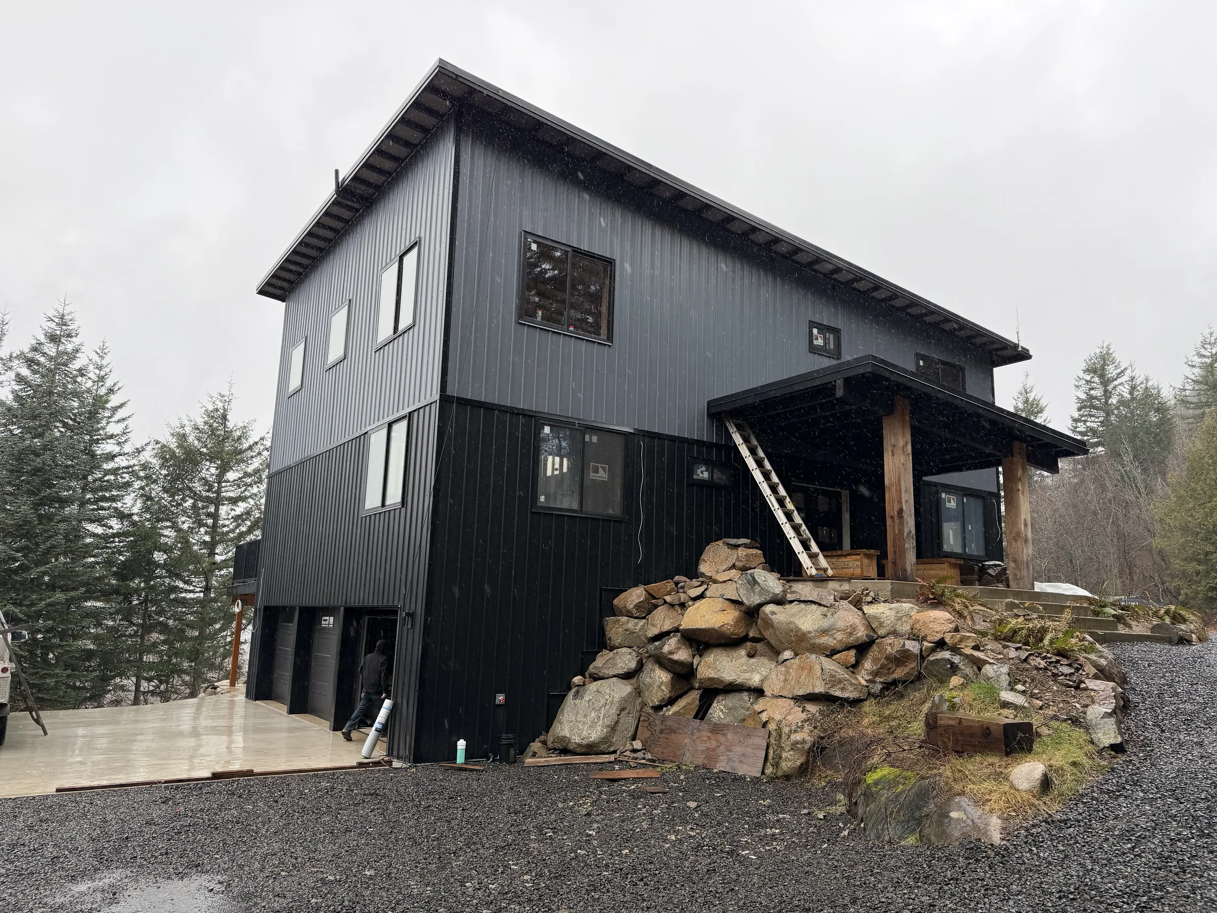 Completed black-clad modern ICF home on a boulder-terraced rise